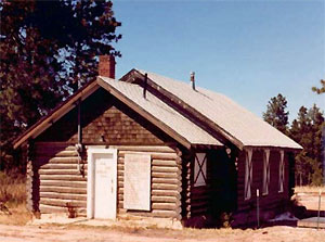 A picture of the school's entrance  with gabled roof and log walls. 