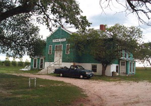 A picture of the turquoise building with white base. There are tree limbs framing the picture on the top corners. 