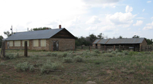 A view of the school with two buildings both long and gabled and some brush between them.